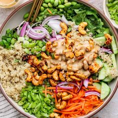 a bowl filled with rice, carrots, and chicken next to some veggies