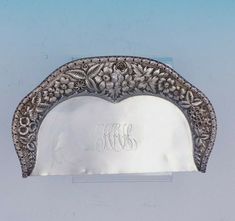 an ornate silver plate with monograms on the front and side, set against a pale blue background