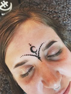 a close up of a woman with a tattoo on her face and eyeliners