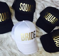 four black and white hats with gold letters that say squad on them, sitting on a fur surface