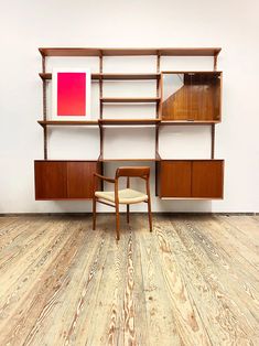 a wooden chair sitting in front of a book shelf on top of a hard wood floor