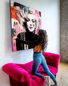 two young women are dancing in front of a painting on the wall behind a pink couch