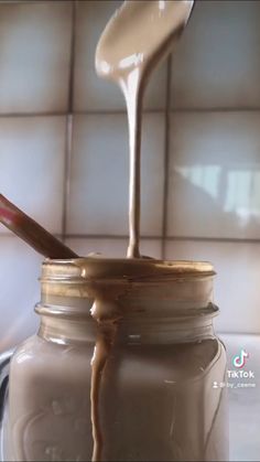 a jar filled with liquid sitting on top of a counter next to a wooden spoon