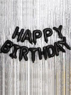 black happy birthday balloons in the shape of letters on a silver foiled curtain background