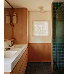 a bathroom with two sinks, a shower and a large window in it's corner