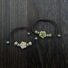 two bracelets with flowers and beads on a wooden surface