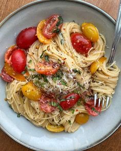 a white bowl filled with pasta, tomatoes and parmesan cheese