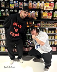 two men standing next to each other in front of a store display filled with food