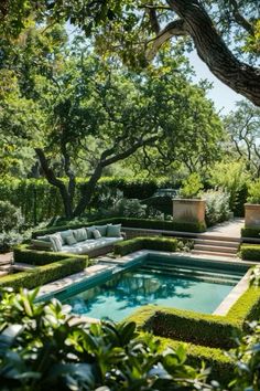 an outdoor swimming pool surrounded by hedges and trees with seating area in the middle is shown