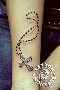 a tattoo on the wrist of a woman with a cross and beads around her ankles