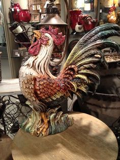 a rooster statue sitting on top of a wooden table next to other items in a store