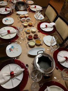 the table is set with white and red plates, silverware and utensils