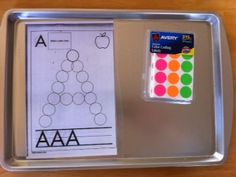 a metal tray with some paper and stickers on top of it next to a ruler