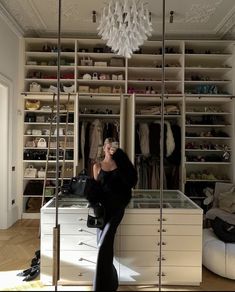 a woman standing in front of a closet full of clothes