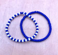 two blue and white beaded bracelets sitting on top of a wooden table