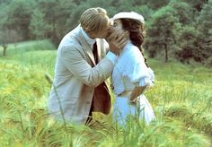 a man and woman kissing in tall grass