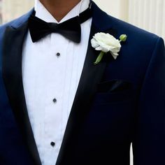 a man in a tuxedo with a white flower on his lapel collar