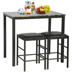 a table with two stools next to it and some fruit on the counter top