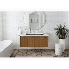 a bathroom with a sink, mirror and bathtub next to a white brick wall