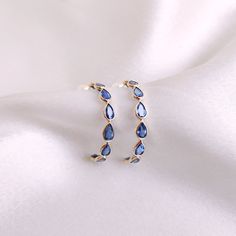 These stunning hoop earrings are set in 14k Solid Yellow Gold with Natural Blue Sapphire with utmost precision. It is an unique and dainty gemstone earring pair for nearly every occasion and is completely hassle-free jewelry. ITEM DETAILS: * Gem: Blue Sapphire * Gem Size: 2.5X4 mm (16pcs) * Gem Shape: Pear Cut * Gem Weight: 3.890 carats * Gold Purity: 14KT * Gold Weight: 1.248 gram * Total Weight of the Earrings: 2.026 gram ✓ The Gold purity is guaranteed and it comes with authentic 14KT gold ha Blue Hoop Earrings With Prong Setting For Anniversary, Elegant Sapphire Hoop Earrings, Fine Jewelry Bezel Set Hoop Earrings As Gift, Bezel Set Hoop Huggie Earrings As Gift, Hoop Huggie Earrings With Bezel Setting As Gift, Elegant Small Hoop Jewelry With Bezel Setting, Elegant Small Hoop Earrings With Bezel Setting, Sapphire Hoop Earrings For Anniversary Fine Jewelry, Elegant Bezel Set Huggie Hoop Earrings