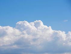 an airplane is flying in the sky with white clouds behind it and a blue sky