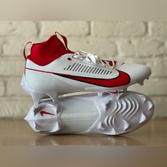 a pair of white and red shoes on top of a wooden table next to a brick wall