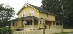 a yellow house with a white picket fence