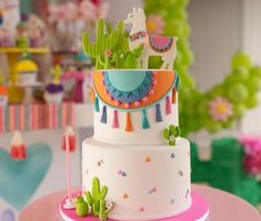 a three tiered cake decorated with cactus and llamas is on a table