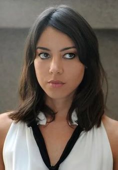 a woman in a white shirt and black tie looking at the camera with an intense look on her face