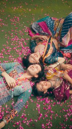 three women laying on the ground covered in flowers