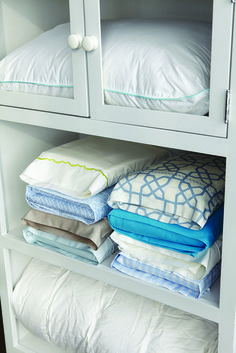 a white cabinet filled with lots of folded blankets and pillow cases on top of each other