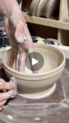 a person is making a bowl out of clay with their hands on the pottery wheel