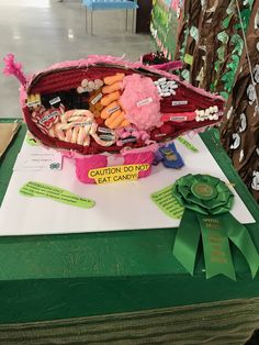 a basket filled with candy and candies sitting on top of a table next to a green ribbon