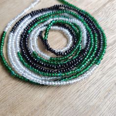 This beautiful waistbead was made with emerald green, iridescent and black glass seed beads.Waistbead length: 50 inches Strung on strong, cotton cord with 2 clear anchor beads (for adjustment) and 2 knots. Tie on, permanent waistbeads. Waist beads have been worn for centuries in African tradition, and the uses are endless. From adornment and weight management, all the way to signs of maturity and femininity, the diversity of waist beads make them appealing pieces of jewelry to own. They are gene Green Tiny Round Beads Waist Beads, Green Beaded Necklace With Black Round Beads, Green Tiny Beads Waist Beads Gift, Green Waist Beads For Gift, Green Beaded Waist Beads For The Beach, Green Beaded Waist Beads For Beach, Green Beaded Necklaces With Black Beads For Festivals, Green Beaded Necklace With Black Beads For Festivals, Green And Black Beaded Necklaces For Festivals