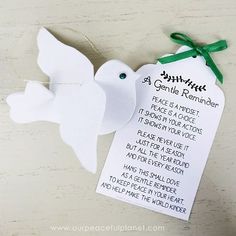 an ornament shaped like a white dove with a green ribbon around its neck