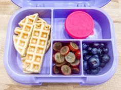 a plastic container filled with different types of food on top of a wooden table next to a pink lid