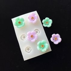 several small flowers are placed on top of a piece of white paper with holes in the middle