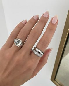 a woman's hand with two rings on it and a mirror in the background