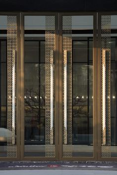 a man walking down a street past tall glass doors that have decorative designs on them