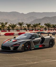 a grey and green sports car driving on a race track with mountains in the background