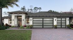 a white house with two garages and palm trees