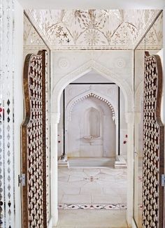 an archway in the middle of a building with white walls and intricate carvings on it