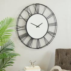 a clock is hanging on the wall next to a table with a potted plant