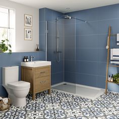 a bathroom with blue walls and tile flooring, including a white toilet next to a walk in shower