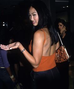 a woman in an orange tank top holding a cell phone