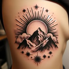 a woman's back with a mountain and stars tattoo on her side ribcage