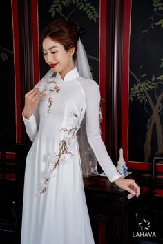 This traditional ao dai is perfect for weddings with its 3D flower details. The classic white color adds elegance and charm to any bride. Handcrafted with intricate details, this ao dai exudes expertise and style. Elegant Fitted Wedding Dress For Traditional Ceremonies, Elegant Ao Dai For Spring Wedding, Fitted White Ao Dai For Ceremonies, Elegant Wedding Ao Dai For Spring, Long Floral Embroidered Wedding Dress, White Floral Embroidery Dresses For Traditional Ceremonies, Traditional Fitted White Wedding Dress, White Floral Embroidered Dress For Traditional Ceremonies, White Long Gown For Spring