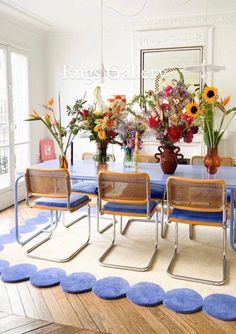 a dining room with blue chairs and flowers in vases