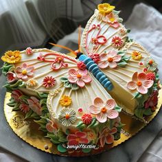 a decorated cake with flowers and a butterfly on it's wings, sitting on top of a table