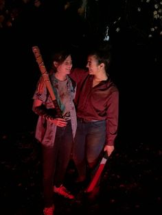 two people standing next to each other in the dark with one holding a baseball bat